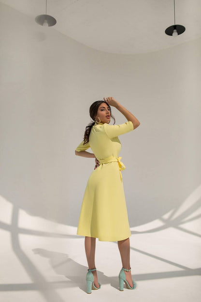 Woman wearing a yellow dress with a belt in a minimalistic setting