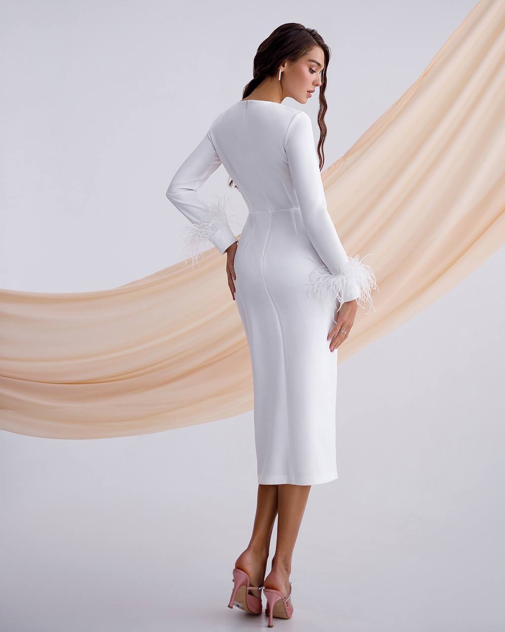 Woman wearing a white long-sleeve dress against a plain background