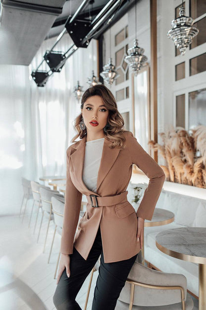 Woman in a beige coat standing in a modern cafe.