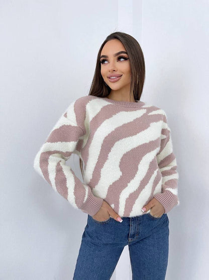 Woman wearing a brown and white patterned sweater with blue jeans on a white background