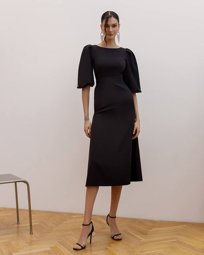 Woman wearing a black dress with puffed sleeves against a plain background