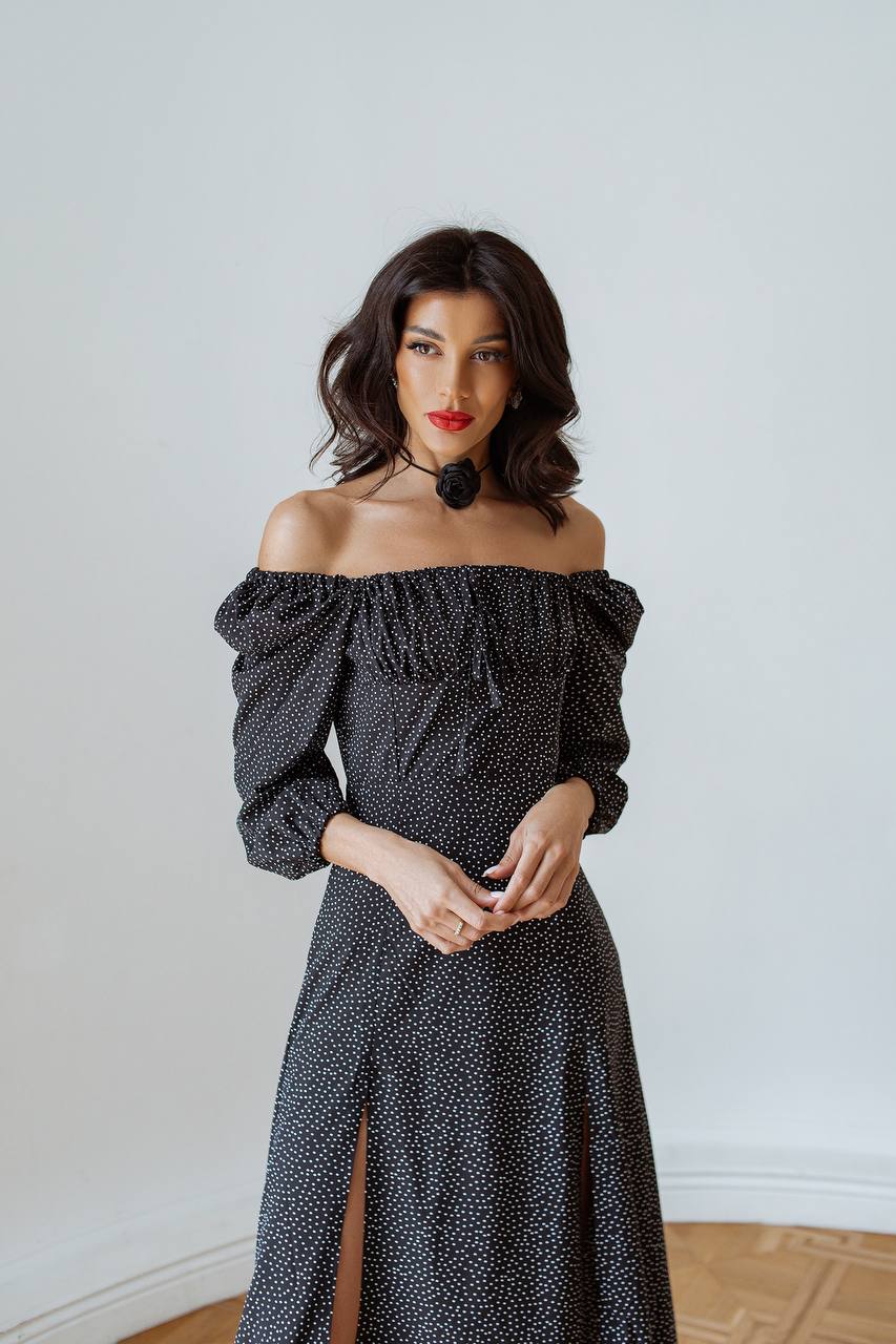 Woman wearing a black off-shoulder dress with a white background