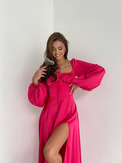 Woman in a bright pink dress posing against a white wall
