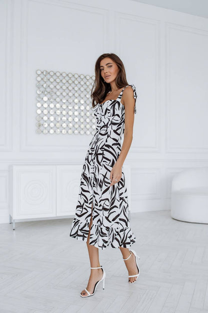 Woman wearing a black and white patterned dress in a minimalistic room.