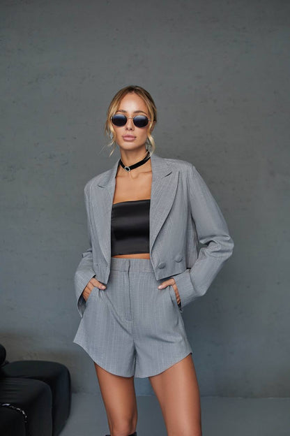 Woman wearing a gray suit and black top against a gray background