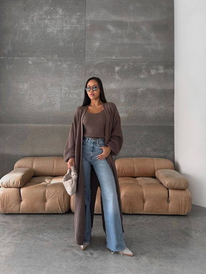 Woman standing in a room with a beige sofa and gray wall.