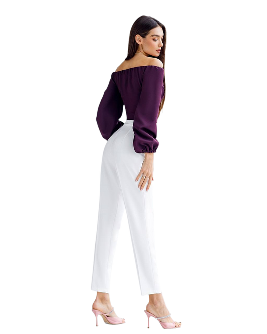 Woman wearing a purple off-shoulder top and white pants on a white background