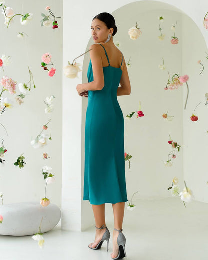 Woman in a teal dress standing in front of a floral wall
