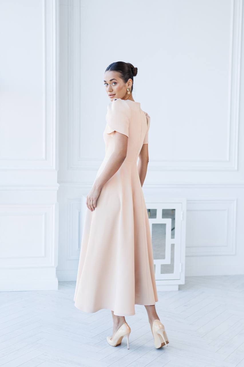 Woman wearing a beige dress in a minimal white room