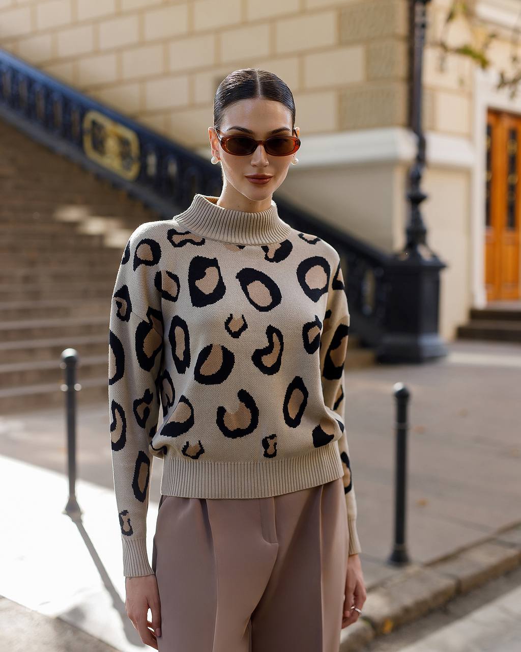 Woman wearing a leopard print sweater and sunglasses on a city street.