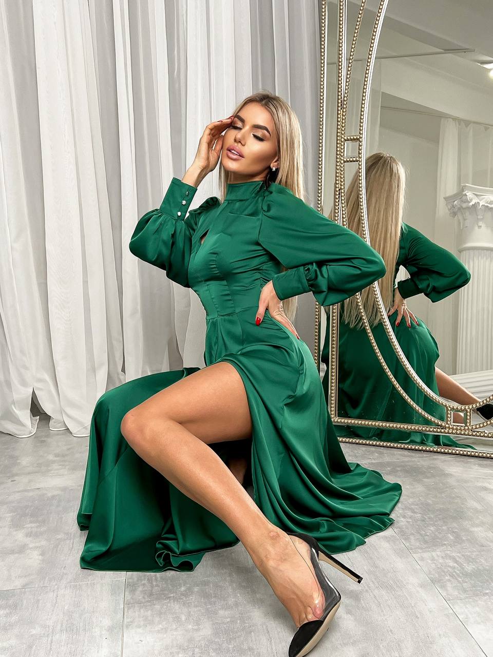 Woman in a green dress posing in front of a mirror.