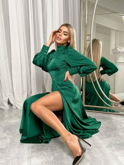 Woman in a green dress posing in front of a mirror.