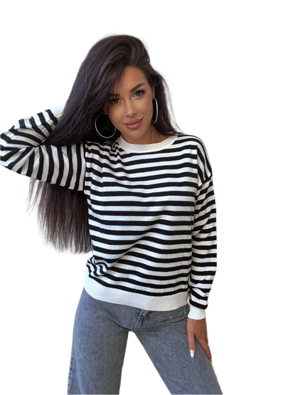 Woman wearing a black and white striped sweater with a plain background