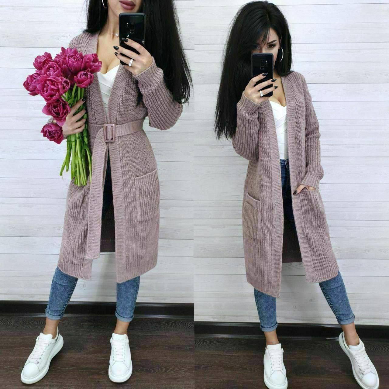 Woman wearing a long pink cardigan with a white background