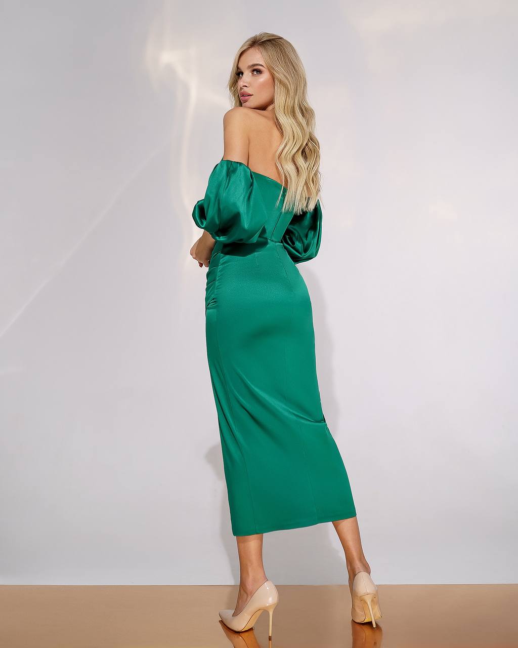 Woman wearing a green off-shoulder dress against a white background