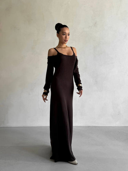 Woman wearing a long dark brown dress against a plain background