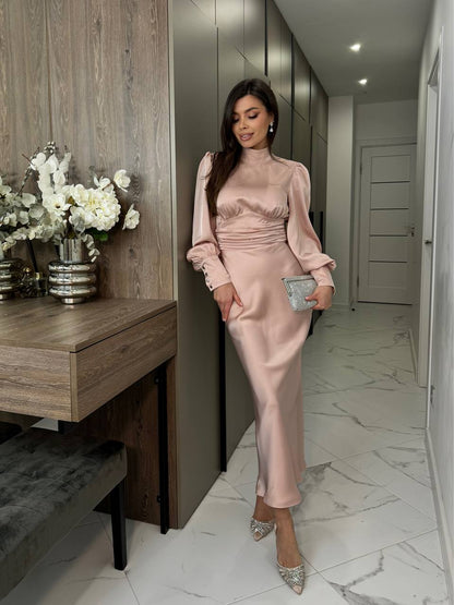 Woman in a pink satin dress standing in a modern interior setting.