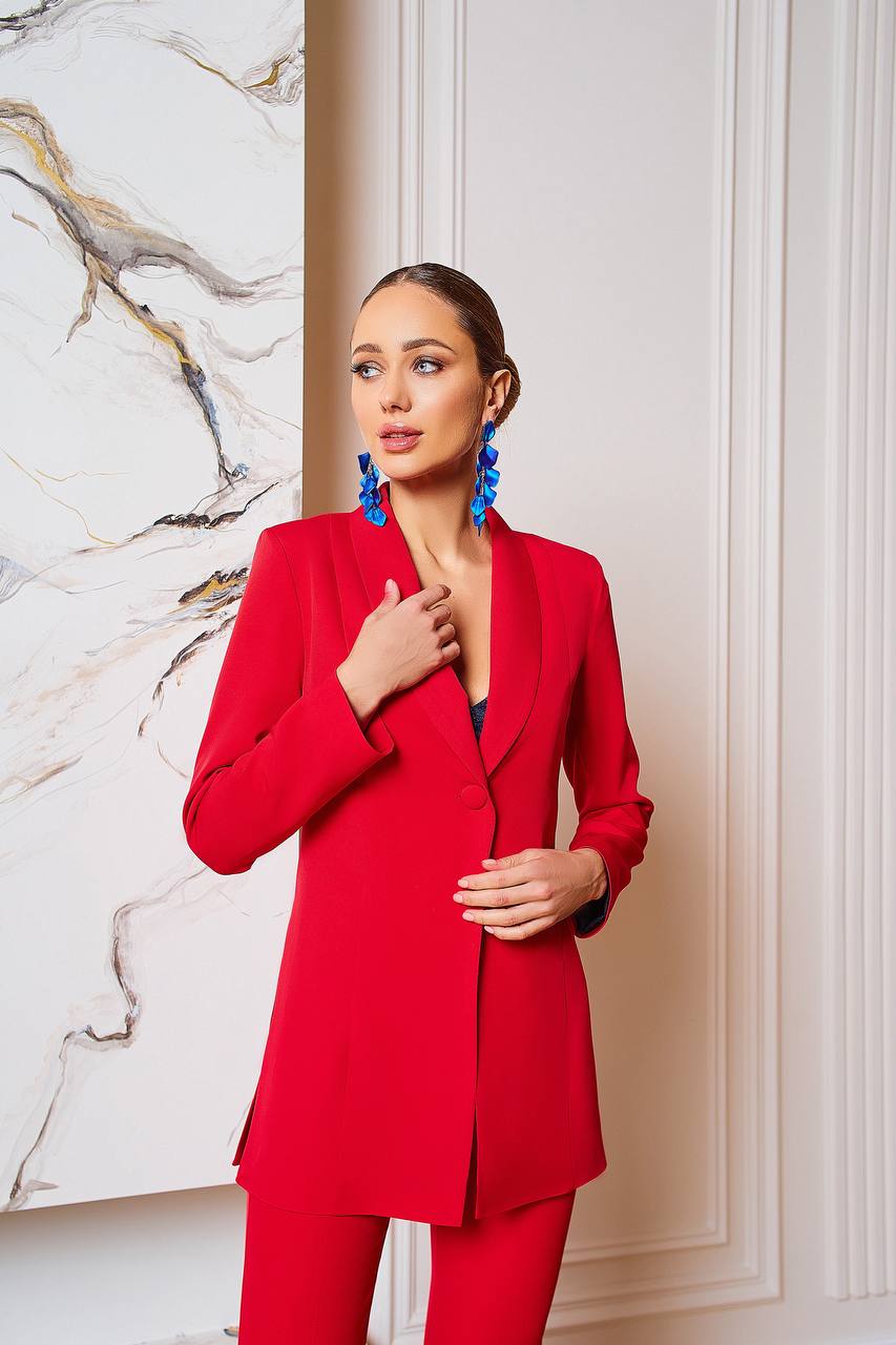 Woman wearing a red suit with a marble wall background