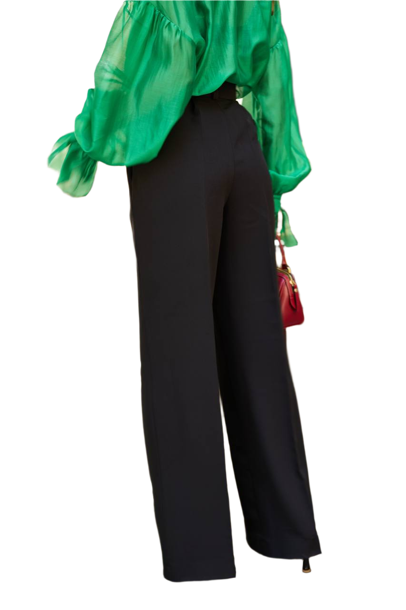 Person wearing a green top and black pants on a white background