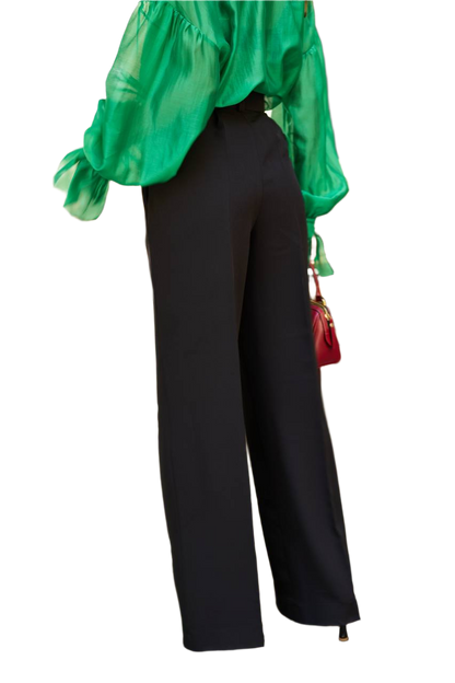 Person wearing a green top and black pants on a white background