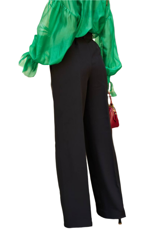 Person wearing a green top and black pants on a white background