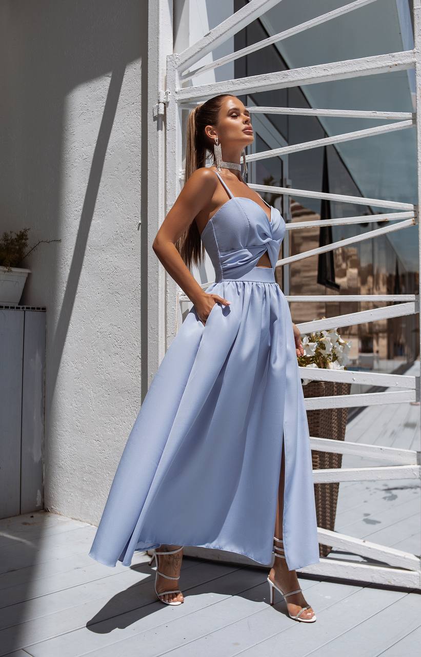 Woman in a light blue dress standing on a balcony with white railings.