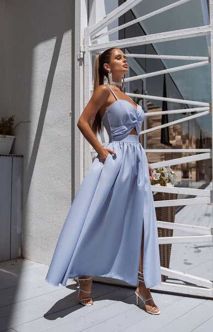 Woman in a light blue dress standing on a balcony with white railings.