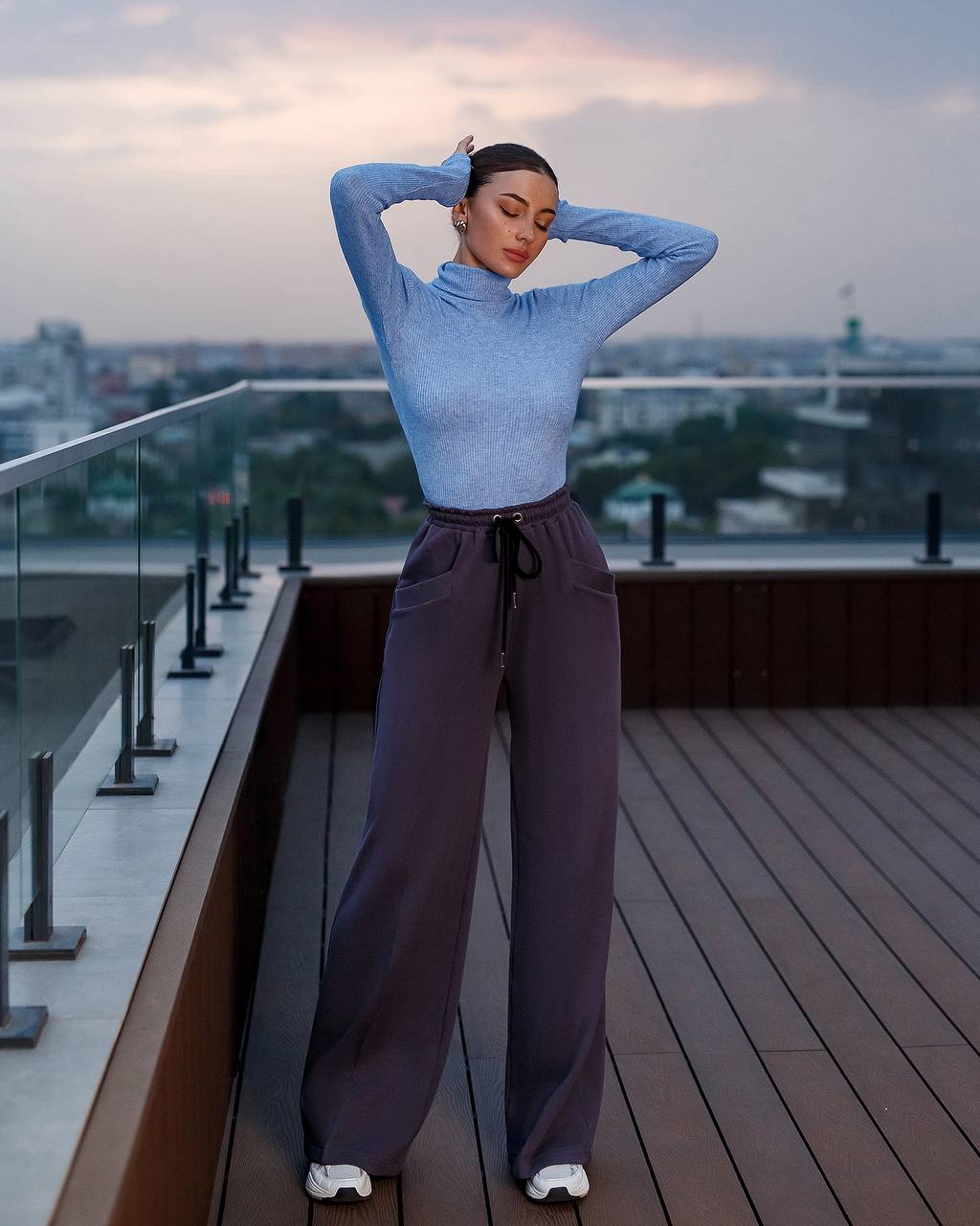 Woman posing on a rooftop with a cityscape background