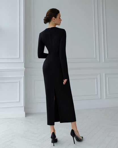 Woman wearing a black dress with a high slit in a white room