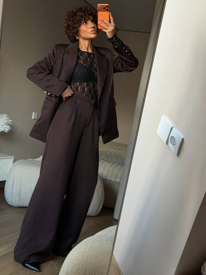 Person taking a mirror selfie wearing a brown suit in a room.