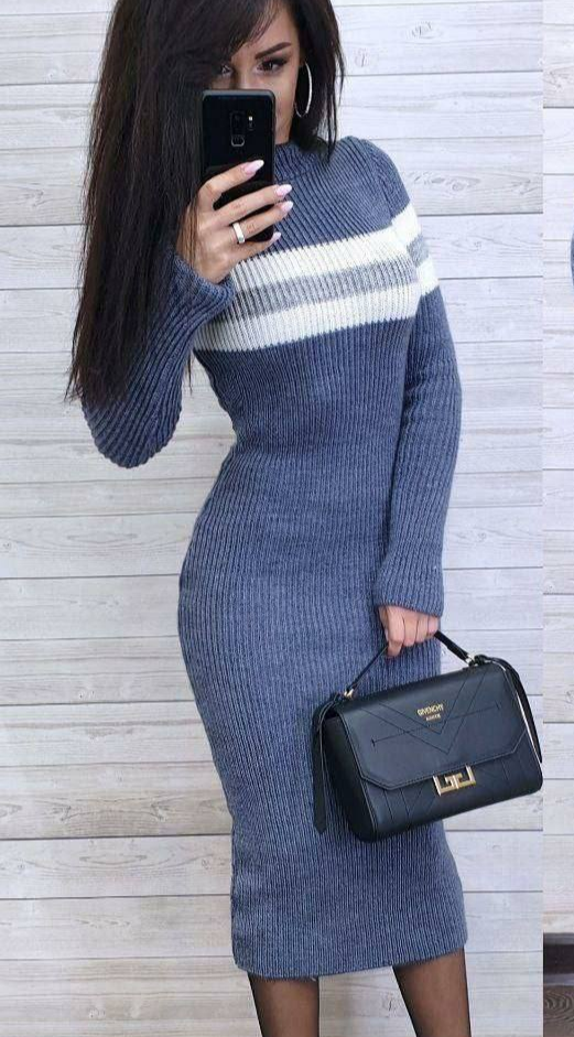 Woman wearing a blue and white striped sweater dress holding a black handbag.