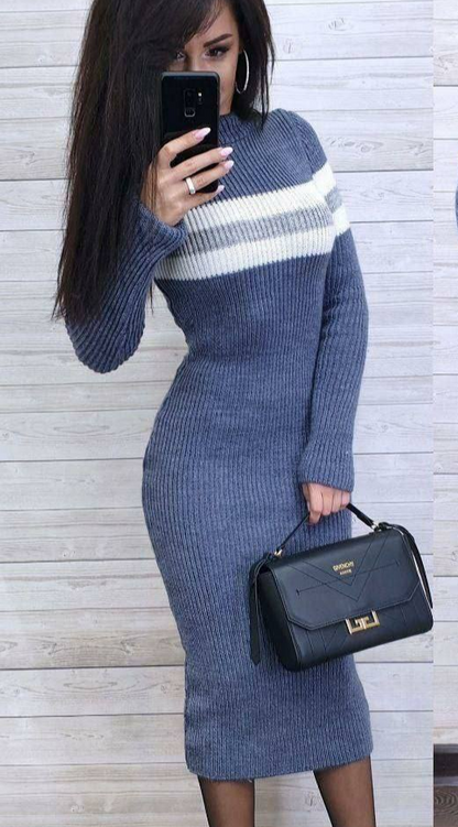 Woman wearing a blue and white striped sweater dress holding a black handbag.