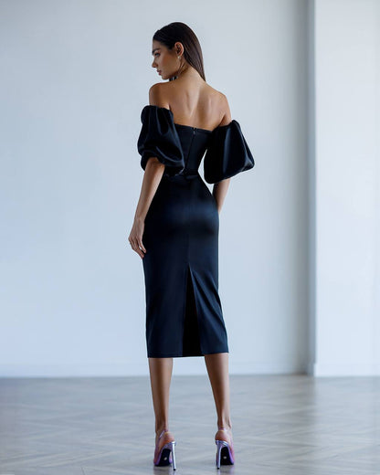 Woman wearing a black off-shoulder dress in a minimalistic setting