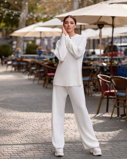 Woman in a white outfit standing in an outdoor cafe setting
