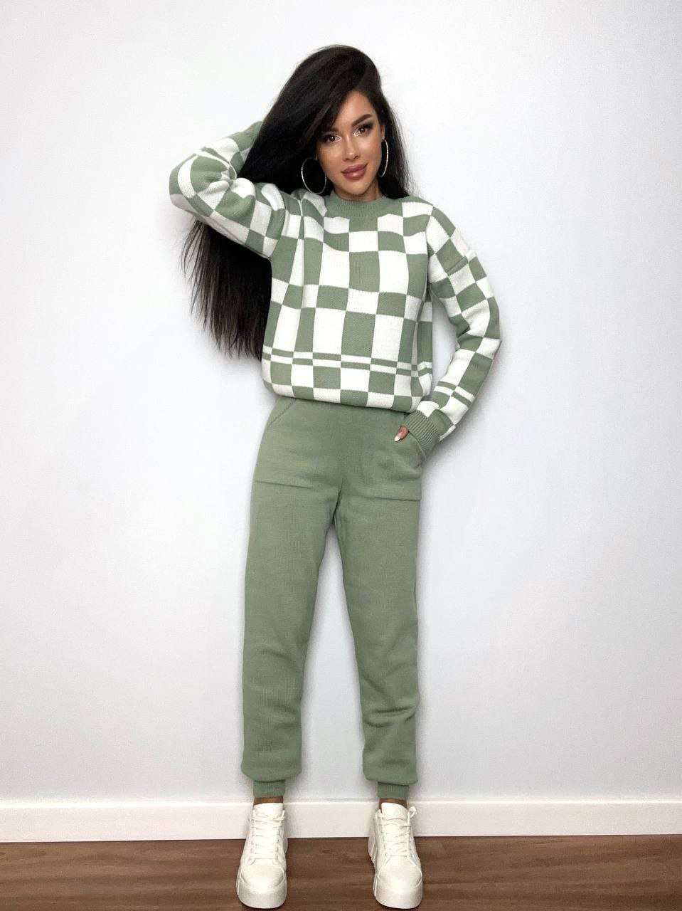 Person wearing a green and white checkered sweater and matching pants against a plain background