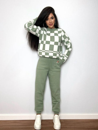 Person wearing a green and white checkered sweater and matching pants against a plain background