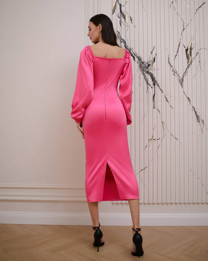 Woman wearing a bright pink dress with long sleeves in an elegant room.