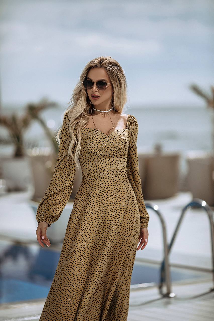 Woman in a leopard print dress standing by a pool with a blurred background