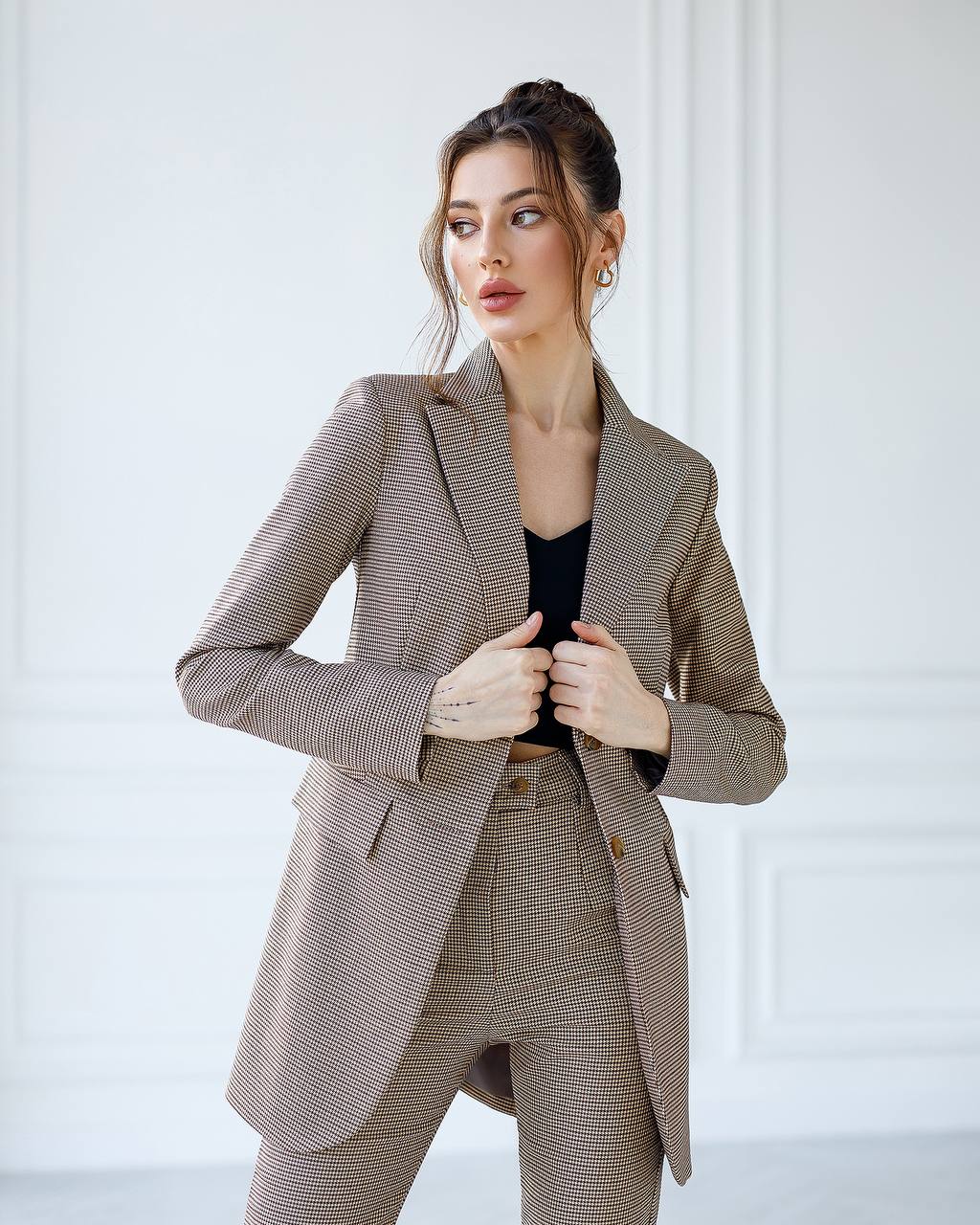 Woman wearing a brown checkered suit against a white background
