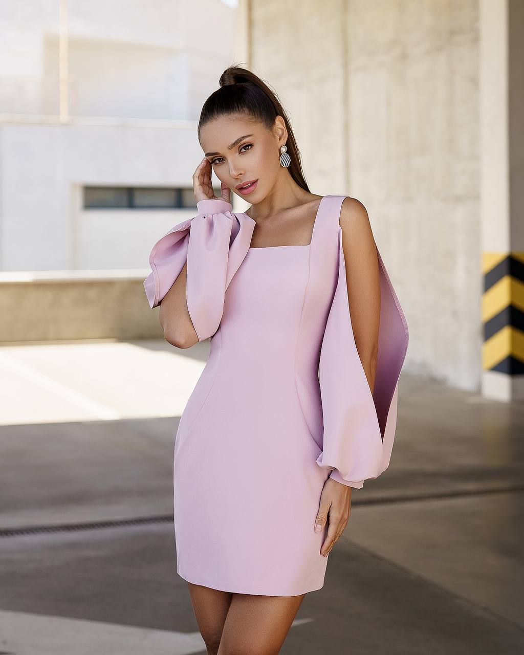 Woman wearing a light purple dress with bow sleeves in an urban setting.