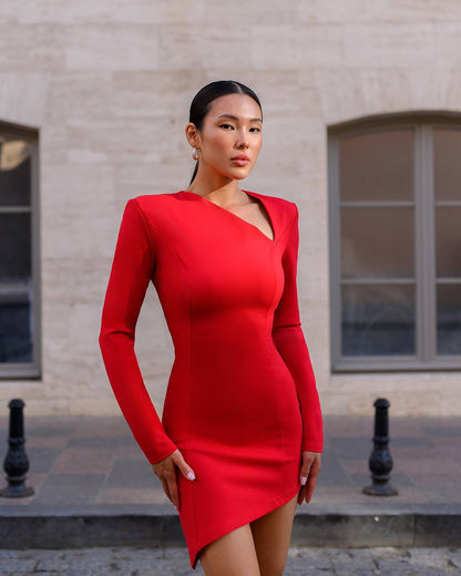 Woman wearing a red dress standing in front of a beige building.