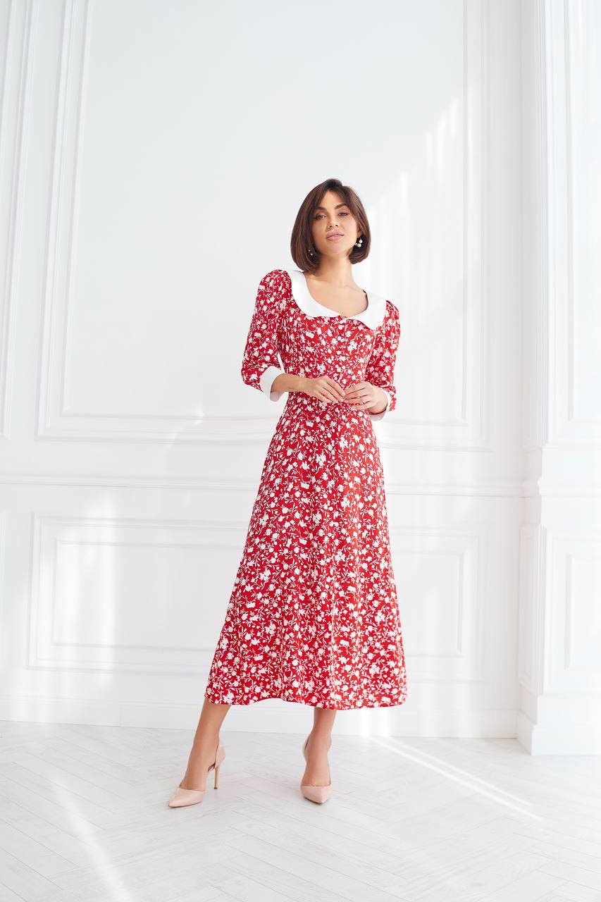 Woman wearing a red floral dress standing against a white background