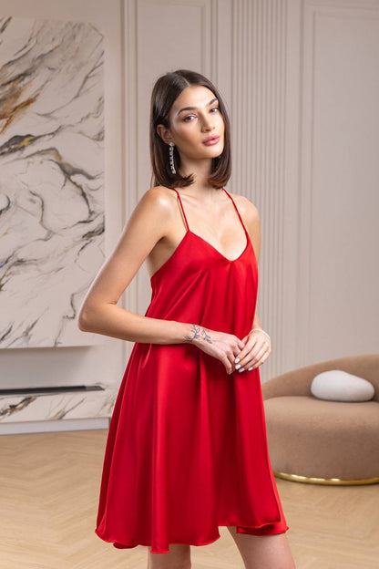 Woman wearing a red dress standing in a room with a marble wall and beige sofa.