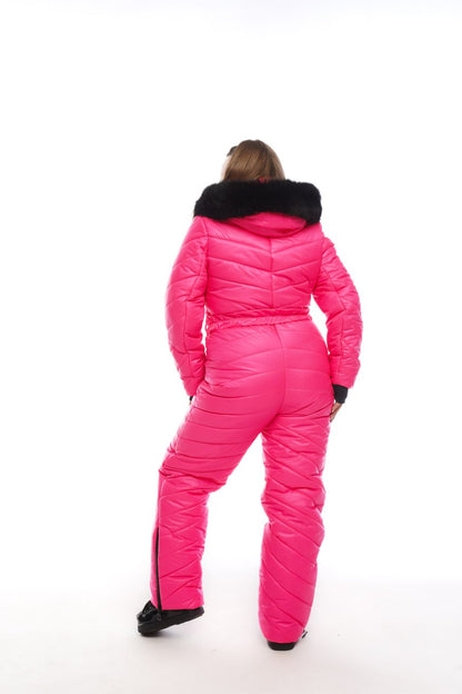 Person wearing a bright pink snowsuit with black fur trim on a white background