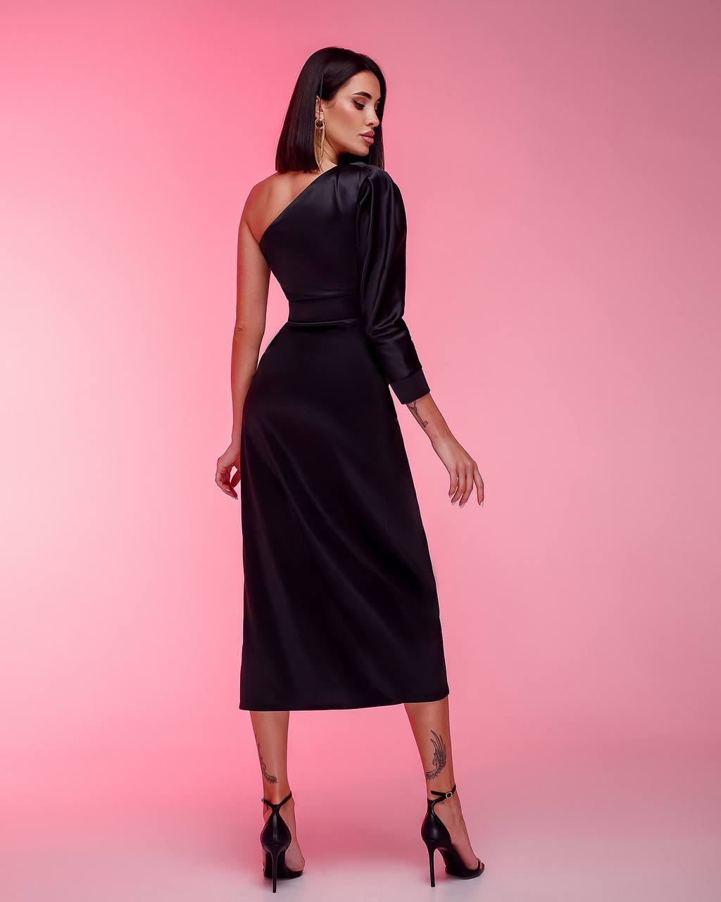 Woman wearing a black one-shoulder dress against a pink background