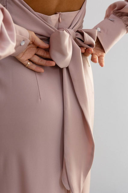 Close-up of a pink dress with a bow detail on a light background