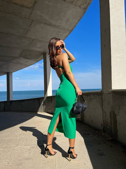 Woman in a green dress standing by a concrete structure with ocean view