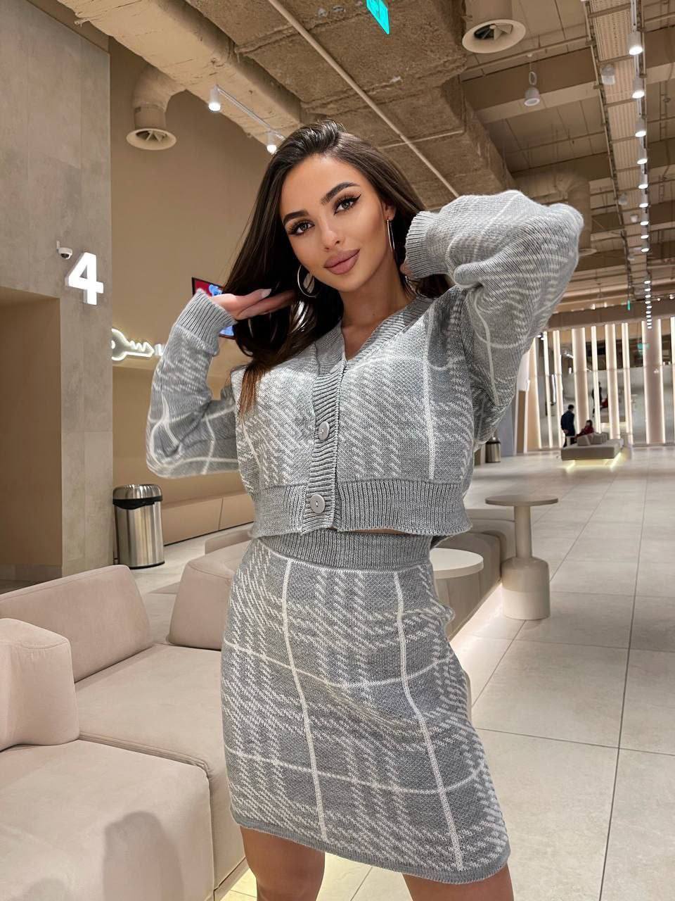 Woman in a gray checkered outfit posing in a modern indoor setting