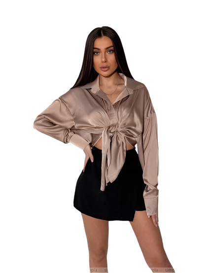 Woman wearing a beige satin shirt with a tie front design on a white background