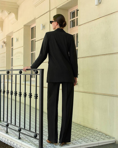 Person in a black suit standing on a balcony of a building.